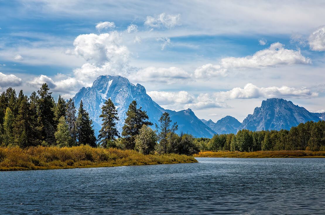 The Grand Teton mountain range behind a lake on a cloudy day